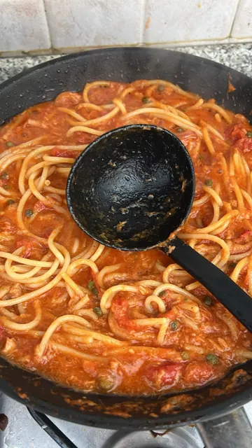 Spaghetti with tomato sauce and a ladle