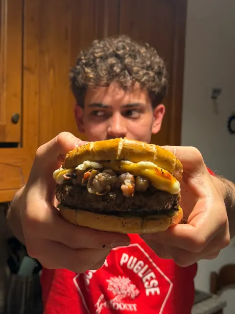 Saverio holding a big burger